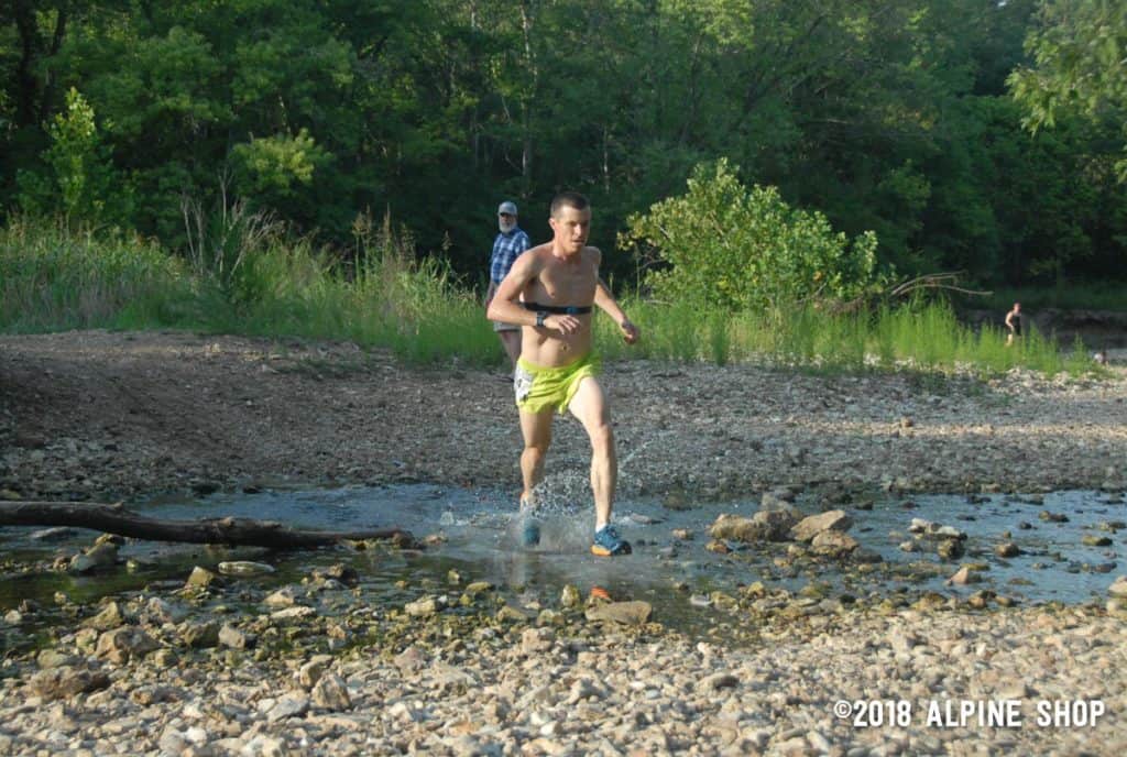 Benjamin Hudson crosses a creek in Trail Run